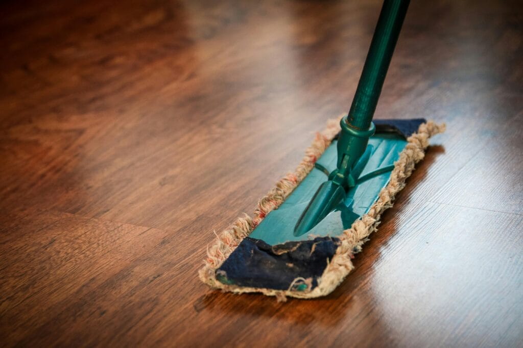 Hard floor cleaning A detailed view of a mop cleaning a wooden floor, showing texture and pattern.