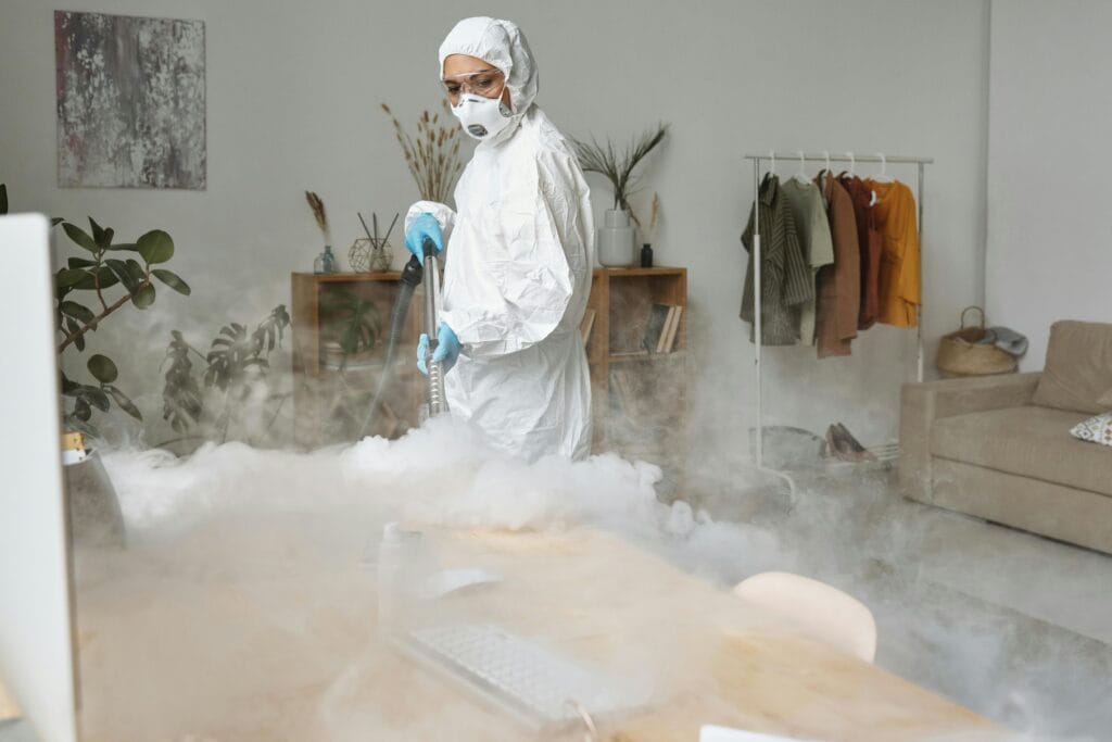 pexels-photo-4176305-4176305 A professional in PPE disinfecting an indoor space using fumigation for safety.